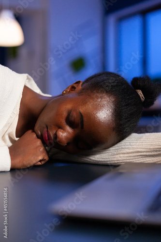 Closeup of tired exhausted african american businesswoman sleeping on desk table late at night in startup office after working at management statistics. Workaholic manager planning company strategy