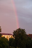 A rainbow in the cloudy sky over the trees and houses of the old West Russian provincial city at Sunny summer evening