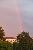 A rainbow in the sky over the trees and houses of the old East European provincial town at summer evening