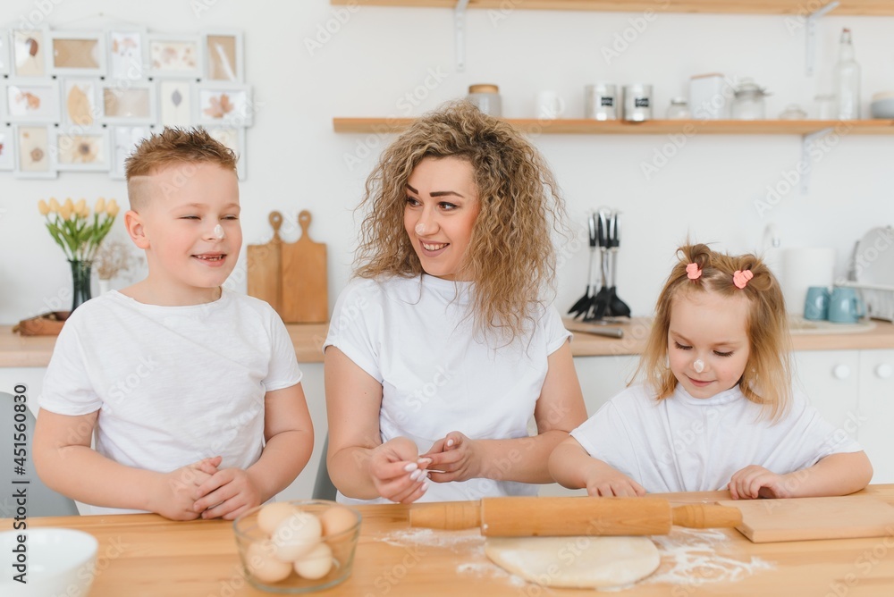 Family learning new recipe together. Happy mom and kids mixing ingredients for homemade cake, pie or cookie dough in the kitchen. Family learning new recipe together. Happy mom and kids mixing ingredients for homemade cake, pie or cookie dough in the kitchen.