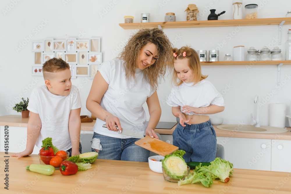 Family in a kitchen. Beautiful mother with children. Lady in white blouse. Family in a kitchen. Beautiful mother with children. Lady in white blouse.
