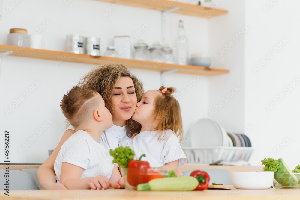 Family in a kitchen. Beautiful mother with children. Lady in white blouse.