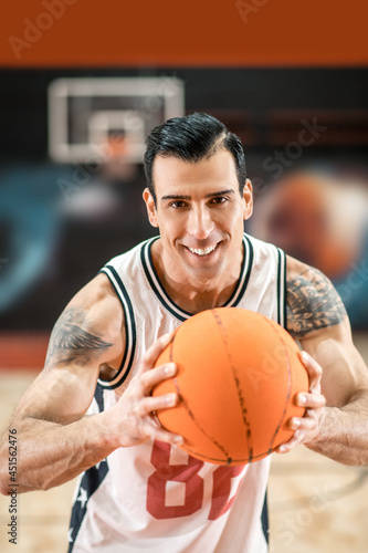 Brunette handsome sportsman holding a big orange ball in hands © zinkevych