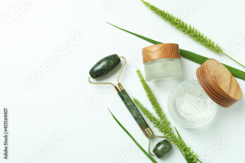 Skin care concept with green face roller on white background