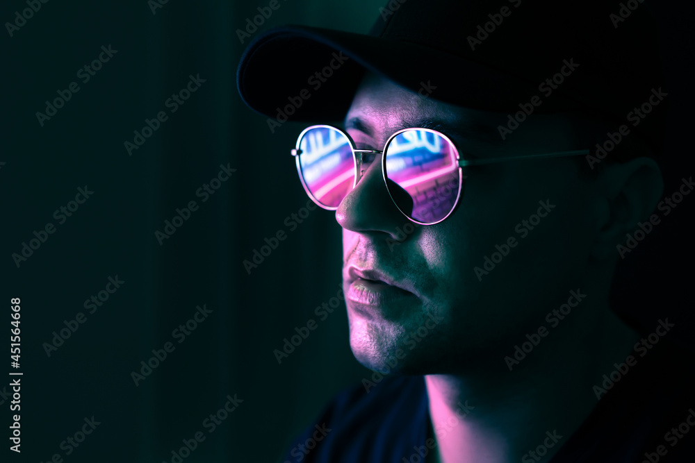 Foto Stock Neon reflection in glasses. Man in fluorescent light from city  led sign. Mysterious cool model in futuristic cyberpunk portrait. Guy in  sunglasses. Techno rave party disco art. Dark black background.