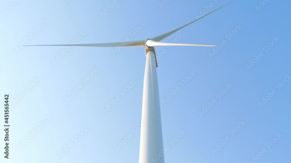 Wind turbine rotating on clear blue sky background. Local eco friendly powerful converter farm generating clean renewable wind energy. Green electricity ecological background farming screensaver 4K Wind turbine rotating on clear blue sky background. Local eco friendly powerful converter farm generating clean renewable wind energy. Green electricity ecological background farming screensaver 4K