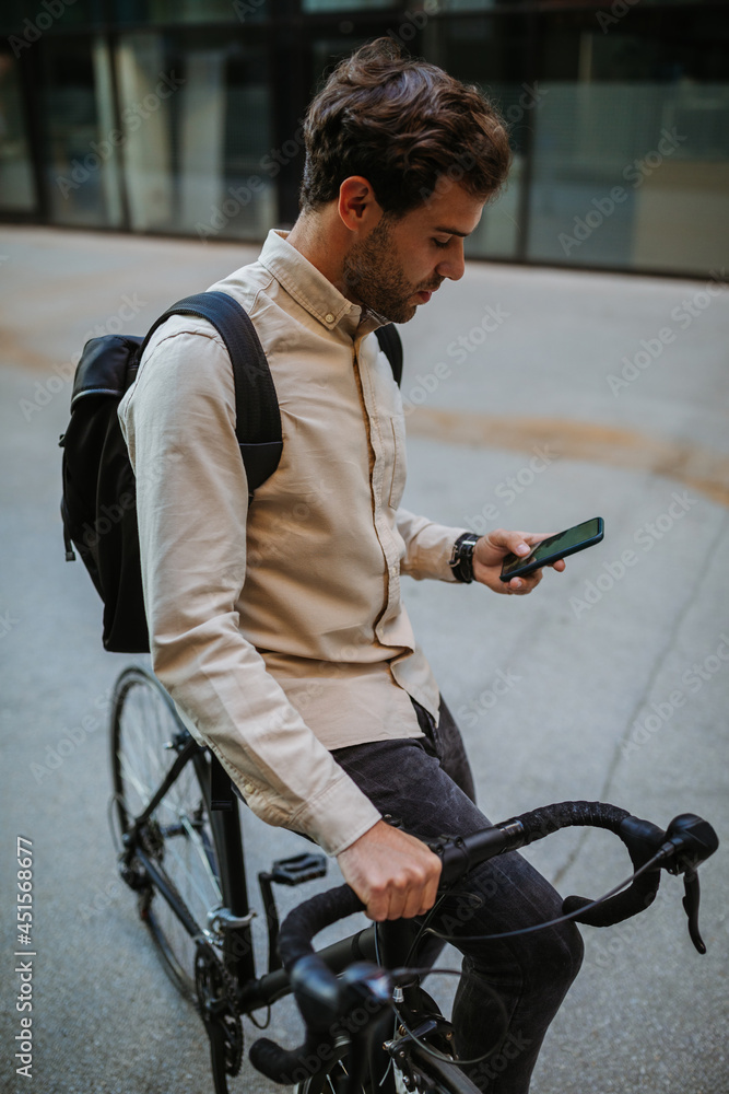 Obraz premium Businessman commuting to work with his bicycle and using phone