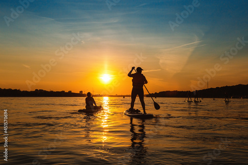 Silhouette man standing up on sapboard. Man ride boat on river at sunset with beautiful view