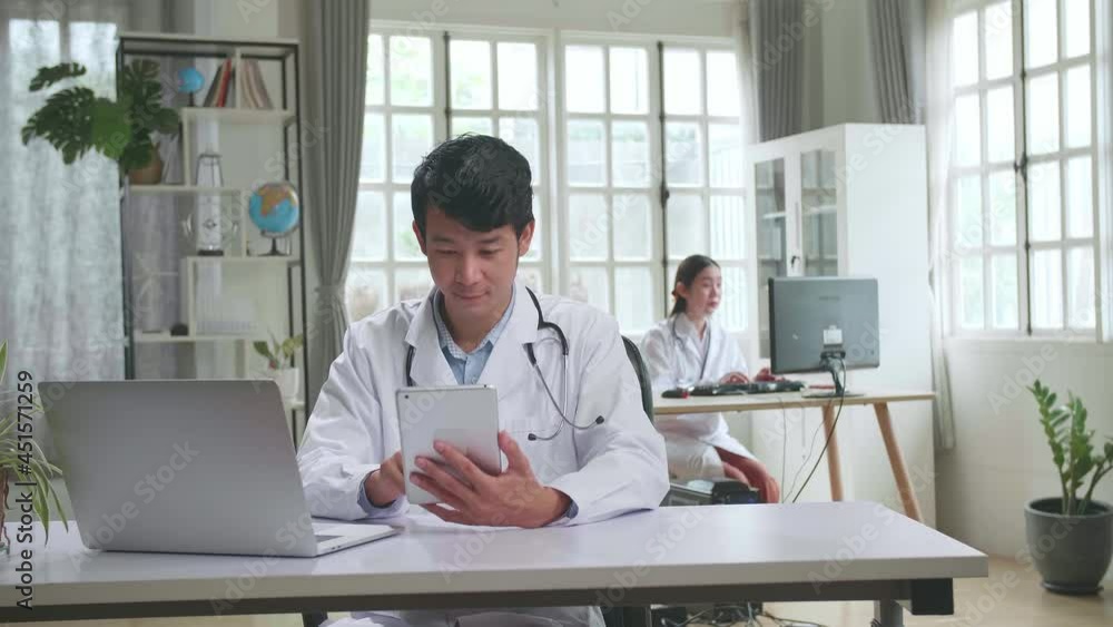 Young Asian Man Doctor Is Using Tablet While Work With Laptop Computer In Workplace. Medical Concept
Young Asian Man Doctor Is Using Tablet While Work With Laptop Computer In Workplace. Medical Concept