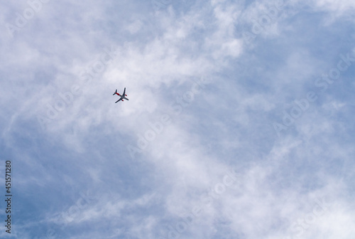 Airplane in a cloudy sky flies from left to right. Passenger or cargo transportation. There is space to add text. 