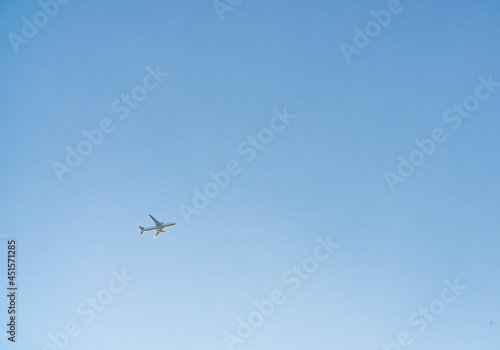 Airplane in a clear blue sky flies from left to right. Passenger or cargo transportation. There is space to add text. 