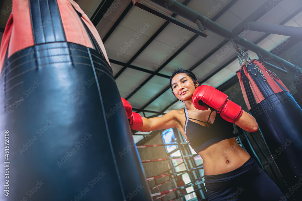 Asian sexy woman doing workout exercise by boxing with sandbag at fitness gym. Selected focus