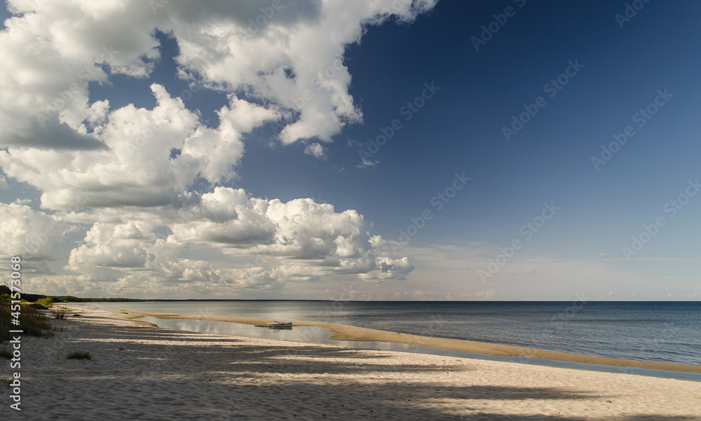 Sea shore on a sunny day with large, white cumulus clouds.