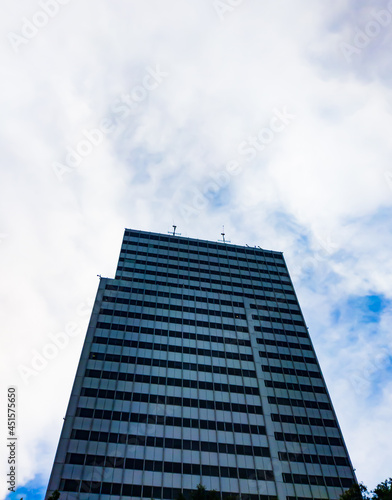Central Jakarta, Indonesia - March 21th, 2021: A tall blue building under a clear sky with fluffy clouds.