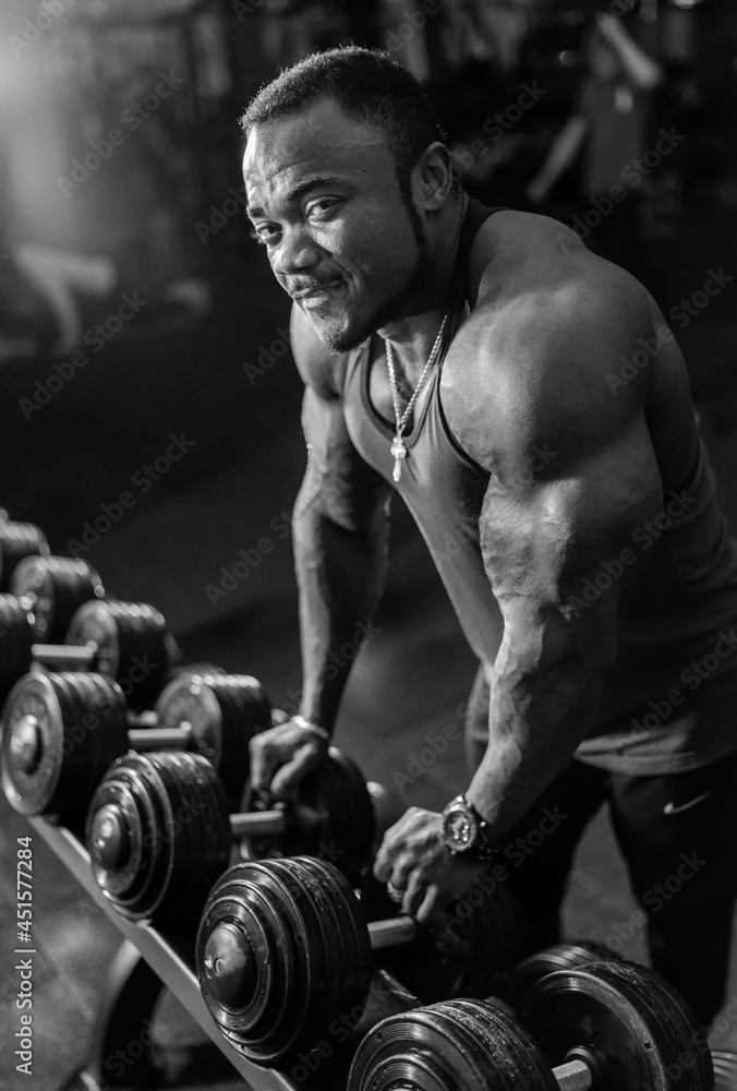 Athlete naked torso man standing in front of a mirror and preparing to exercises with dumbbells in the gym,. Lifestyle health concept. Black and white photo Athlete naked torso man standing in front of a mirror and preparing to exercises with dumbbells in the gym,. Lifestyle health concept. Black and white photo