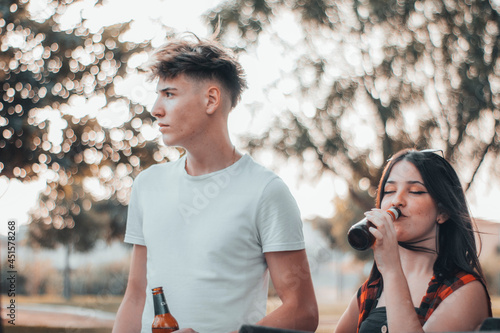 Muchacho y chica joven en una barbacoa al aire libre con bebiendo bebidas de alcohol 