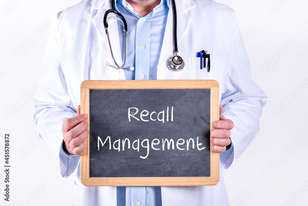 Hausarzt in der Arztpraxis mit einer Tafel auf der Recall Management steht Hausarzt in der Arztpraxis mit einer Tafel auf der Recall Management steht