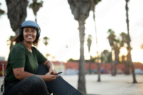 Portrait of happy african-american woman relaxing outdoors. Happy woman sitting and listening the music .