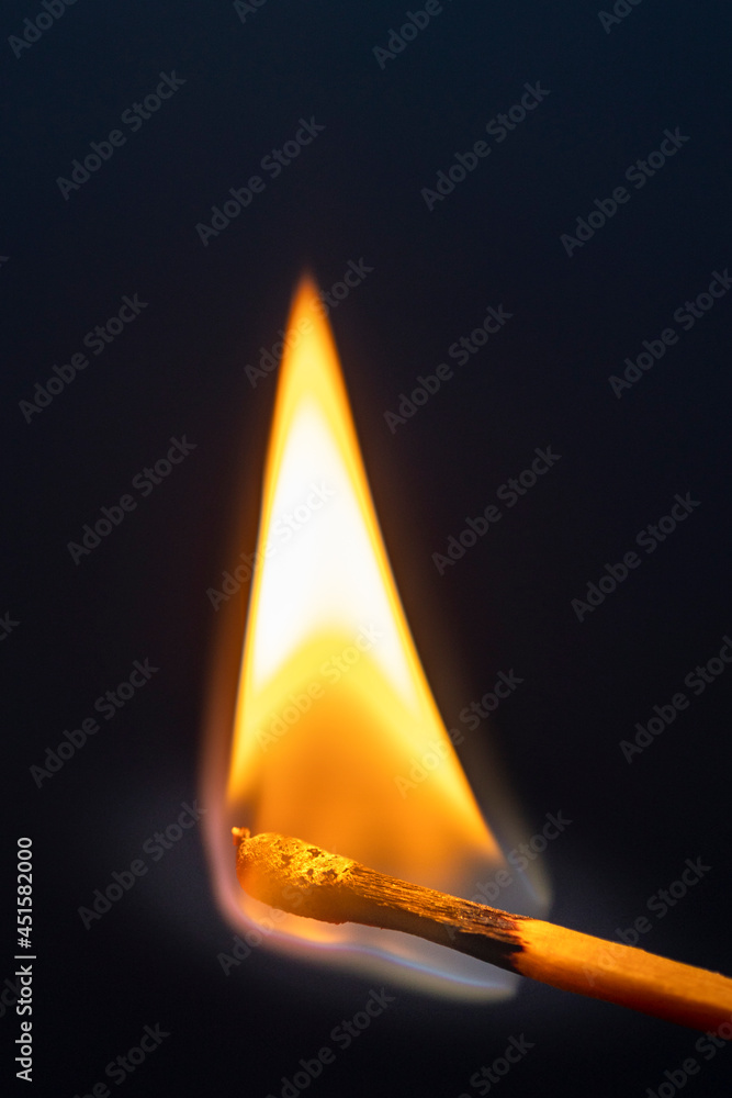 Ein brennendes Streichholz wird von Fingern gehalten vor blauem Hintergrund Ein brennendes Streichholz wird von Fingern gehalten vor blauem Hintergrund