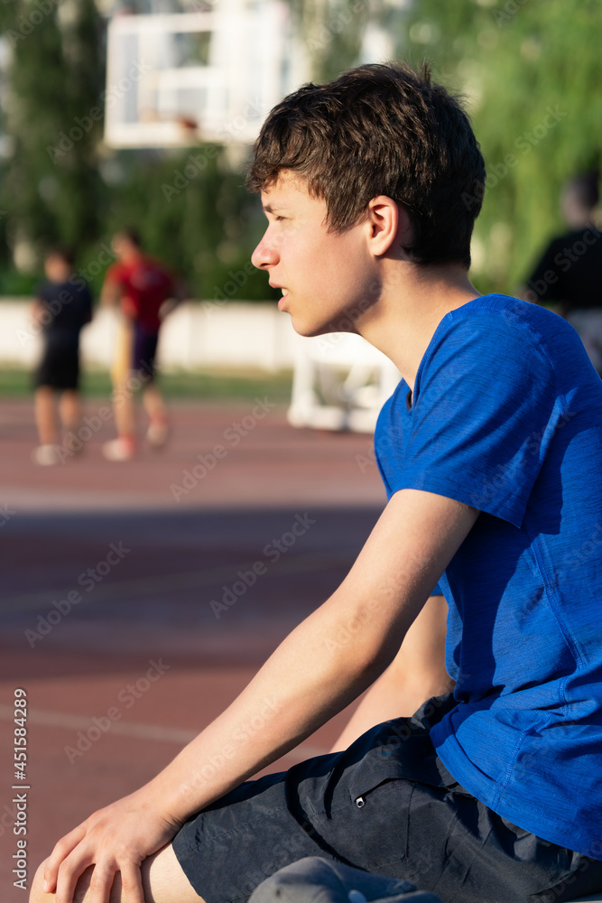 the guy is sitting on the edge of the field and watching a basketball game the guy is sitting on the edge of the field and watching a basketball game
