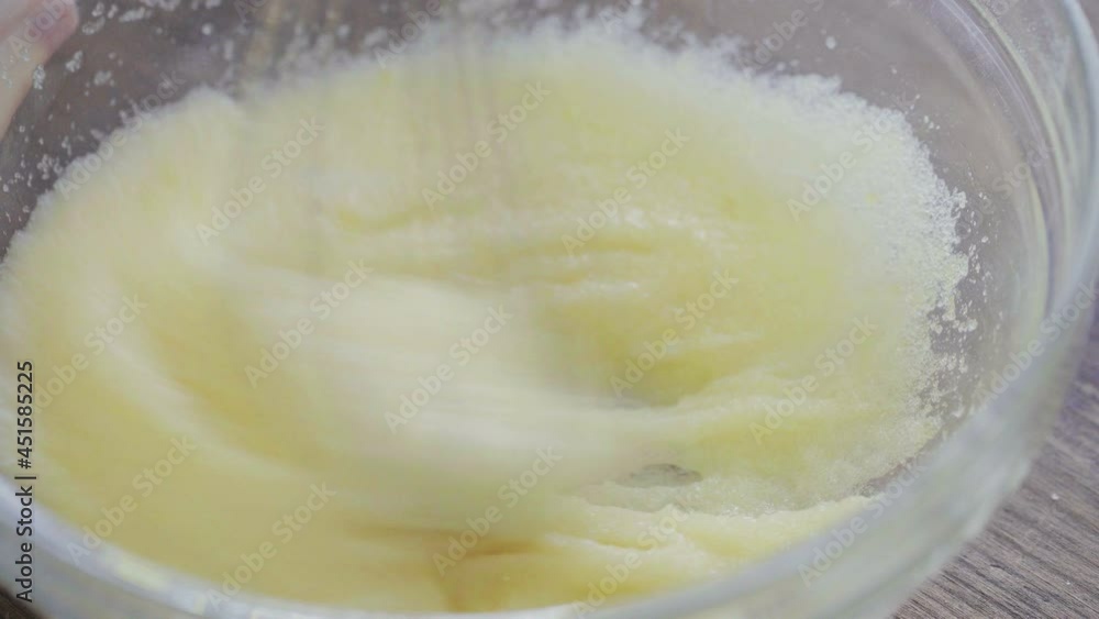 Baker hands knead the dough with a whisk in a glass bowl. Cooking dough, baking ingredients, top view Baker hands knead the dough with a whisk in a glass bowl. Cooking dough, baking ingredients, top view