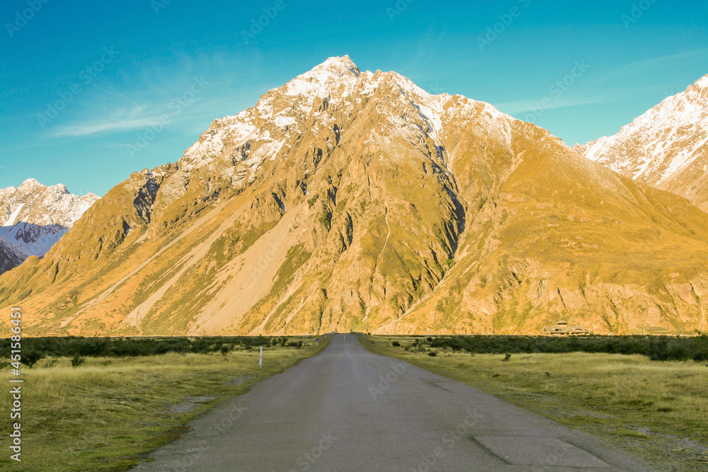 Road leading to a large mountain among flat lands in New Zealand