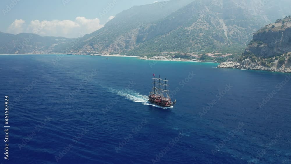 Amazing panoramic aerial 4k view from drone of tourism pirate ship going from Oludeniz to Butterfly Valley and Kabak Valley along steep cliffs and beautiful bays on a bright and sunny day in Fethiye Amazing panoramic aerial 4k view from drone of tourism pirate ship going from Oludeniz to Butterfly Valley and Kabak Valley along steep cliffs and beautiful bays on a bright and sunny day in Fethiye