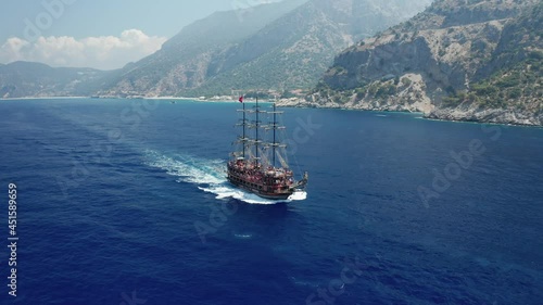 Amazing panoramic aerial 4k view from drone of tourism pirate ship going from Oludeniz to Butterfly Valley and Kabak Valley  along steep cliffs and beautiful bays on a bright and sunny day in Fethiye 