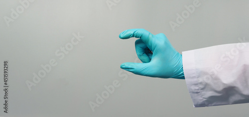 Hand is do holding gesture and wear doctor gown and blue medical glove on grey background.