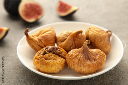 Group of dried figs in a bowl on grey background.