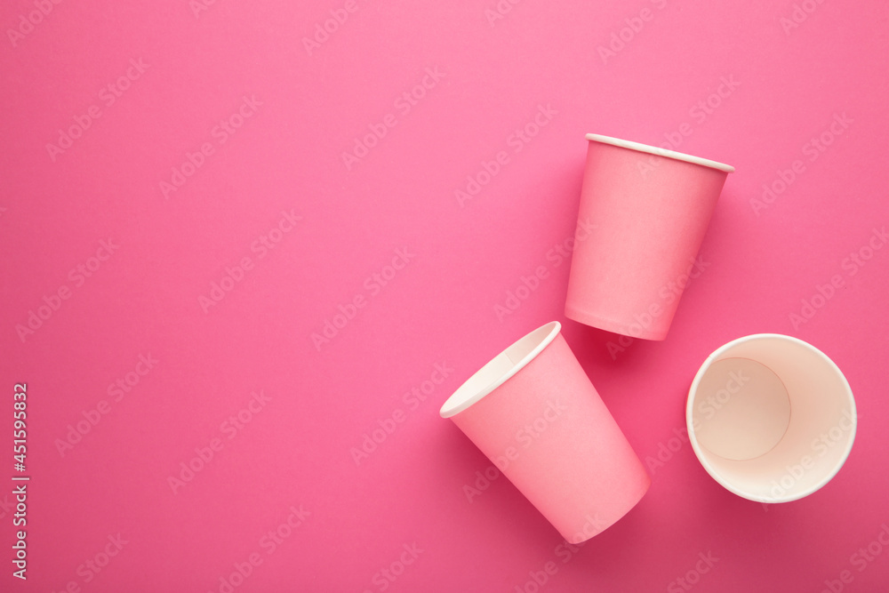 Disposable paper cups on pink background. Top view. Disposable paper cups on pink background. Top view.