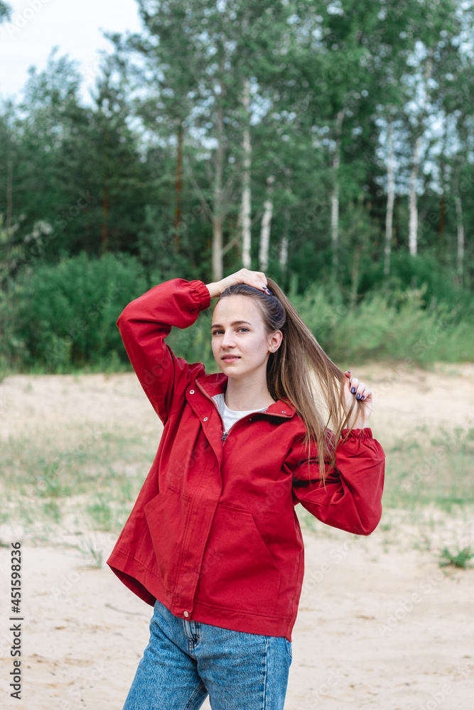Candid portrait of a young caucasian woman in red clothes playing with her hair, posing
