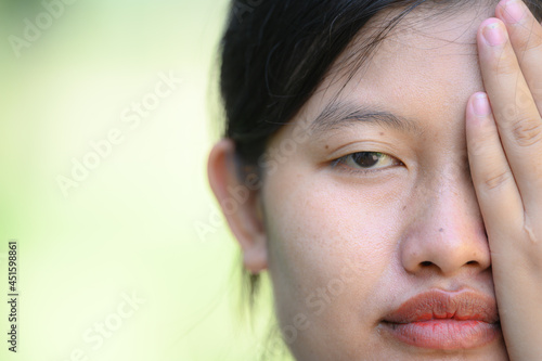The face of an Asian woman has one hand covering her face.face without makeup