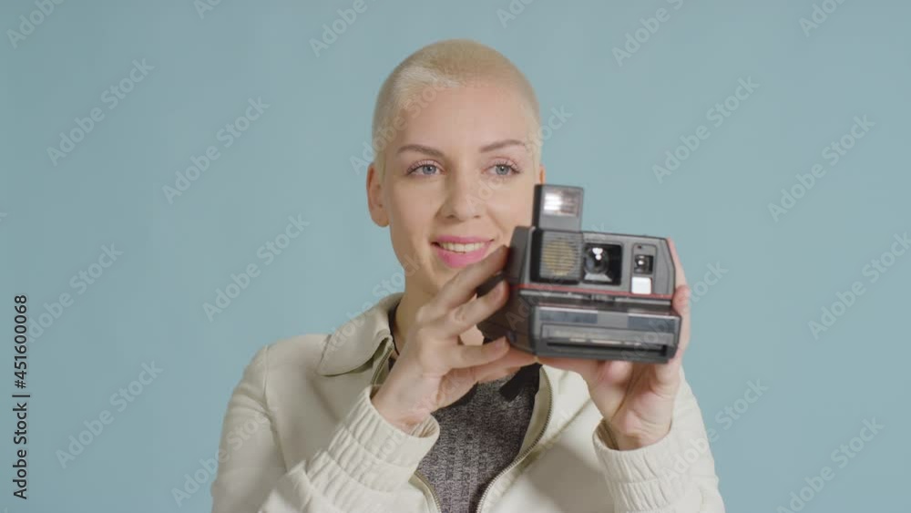 Female caucasian model posing with instant film camera against blue backdrop 01 Female caucasian model posing with instant film camera against blue backdrop 01