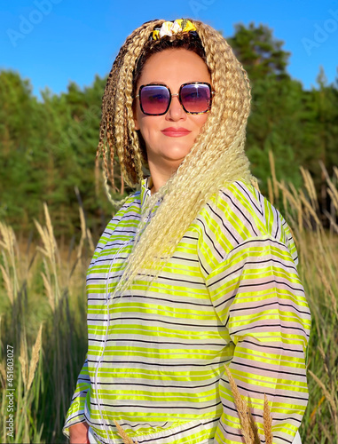 Pretty woman with curly hair stands on the sand dune and looks at the sunset over the Baltic Sea in Vecaki, Latvia photo