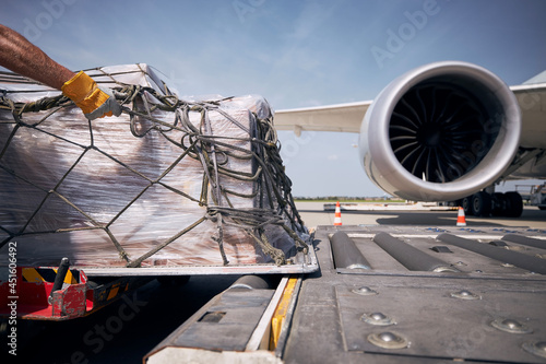 Hand of ground crew during unloading freight airplane. Cargo containers against jet engine of plane...