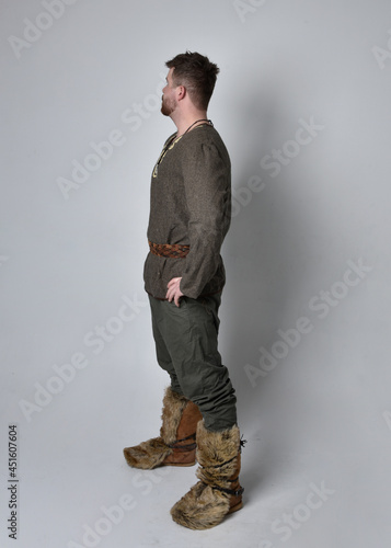 Full length portrait of young handsome man wearing medieval Celtic adventurer costume. Standing pose isolated on studio background.