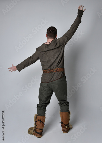 Full length  portrait of  young handsome man  wearing  medieval Celtic adventurer costume.  Standing pose isolated on studio background. photo