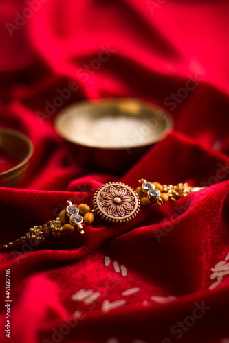 Canvas Print Raksha Bandhan background with an elegant Rakhi and Rice Grains on red cloth textured background