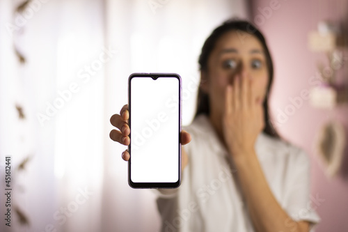 Mujer sorprendida sosteniendo celular.