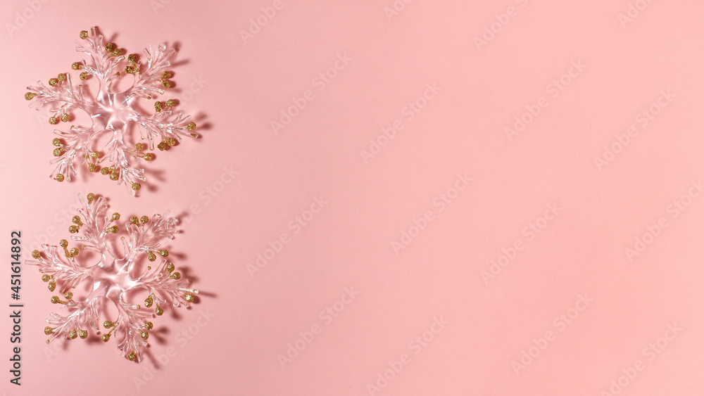 Banner of two transparent snowflakes with golden glitters at the tips on a bright pink background on the left side. Christmas concept lat lay top view with copy space Banner of two transparent snowflakes with golden glitters at the tips on a bright pink background on the left side. Christmas concept lat lay top view with copy space