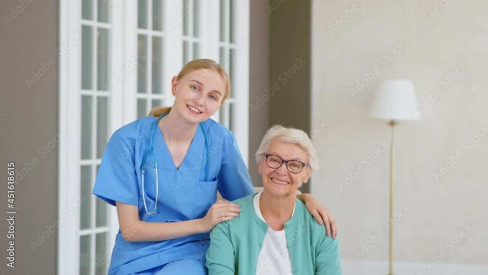 Doctor with stethoscope hugs senior woman posing in room Doctor with stethoscope hugs senior woman posing in room