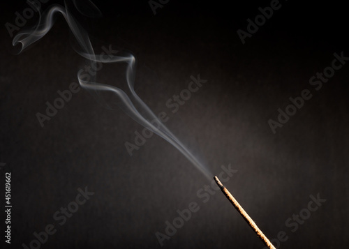 incense stick with smoke against black background 