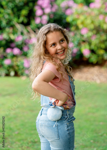 little girl in pink t-shirt and jeans walking in park on summer day