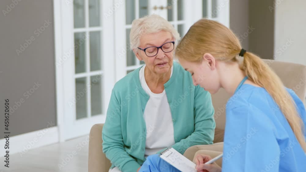 Doctor interviews old lady patient making notes in office Doctor interviews old lady patient making notes in office