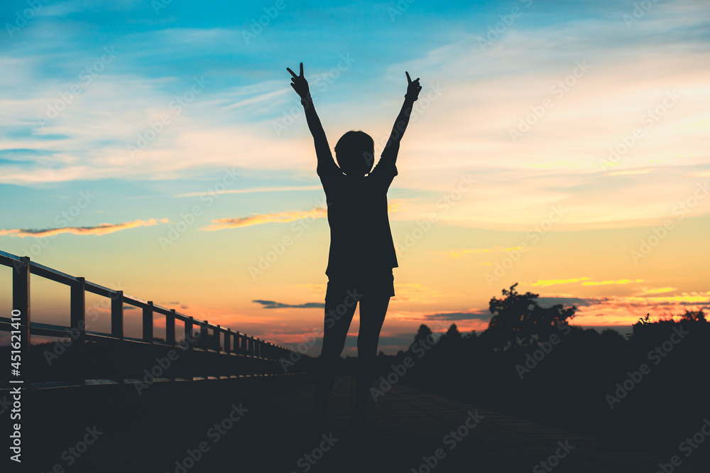 Fototapeta premium Happy celebrating winning success woman at sunset or sunrise standing elated with arms raised up.