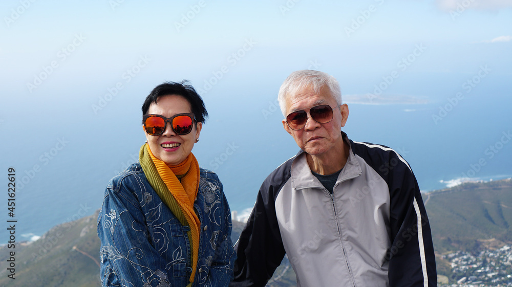 Asian senior elderly travel to South Africa on peak top of table mountain scenic view over Cape town city ocean bay