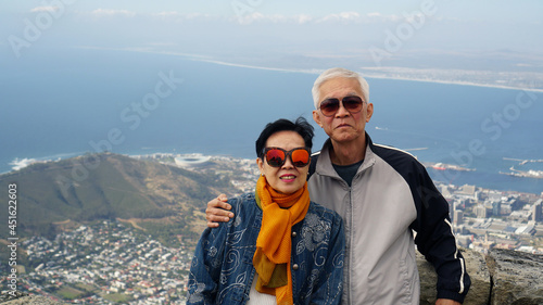 Asian senior elderly travel to South Africa on peak top of table mountain scenic view over Cape town city ocean bay