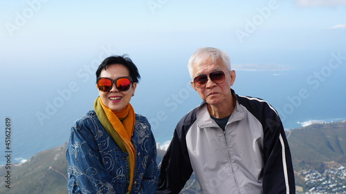 Asian senior elderly travel to South Africa on peak top of table mountain scenic view over Cape town city ocean bay