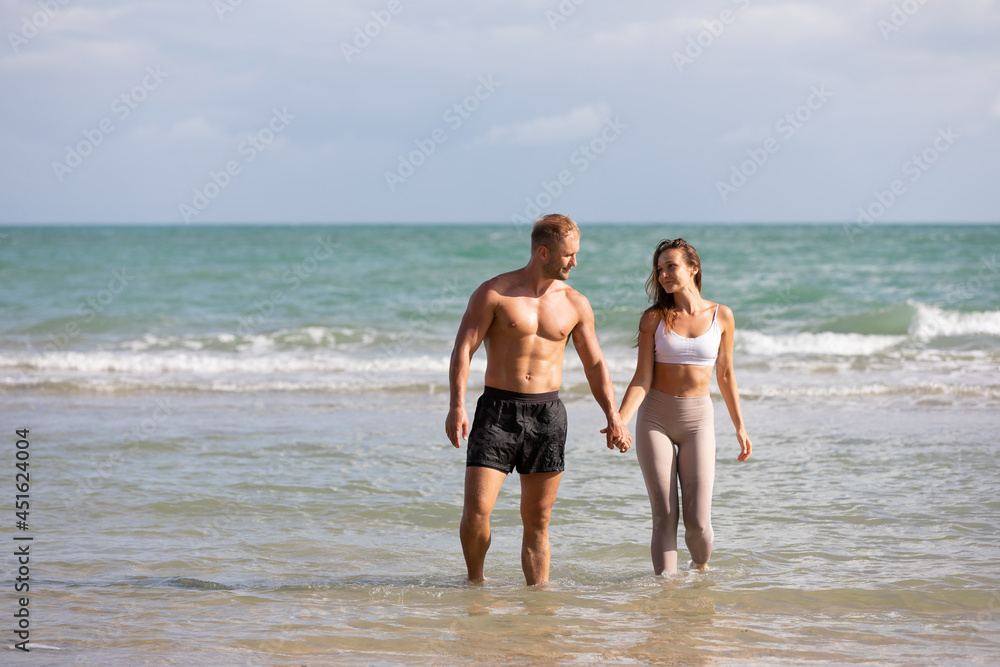 happy couple walking and splashing water on the sea in summer day
